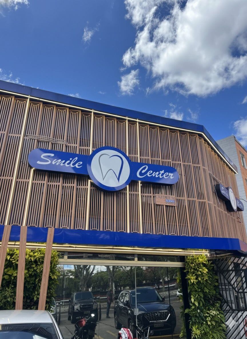 Fachada da clínica Smile Center em José Bonifácio, Zona Leste SP, com letreiro azul iluminado e arquitetura moderna. Entre em contato via telefone. Fale Conosco!