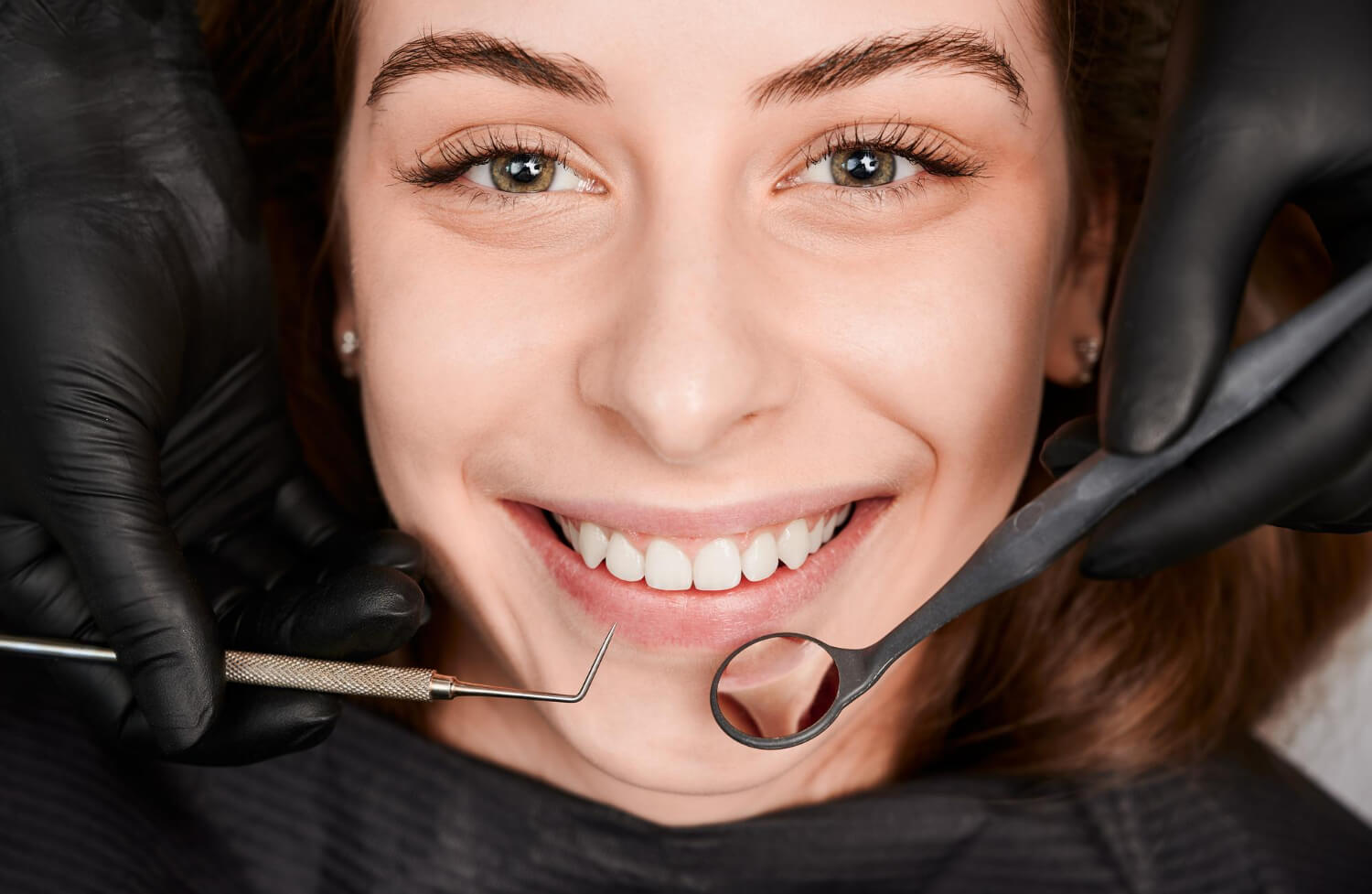 Dentista usa espelho clínico avaliando dor e tratamento de canal de paciente na Clínica Smile Center Odontologia na Zona Leste - SP.