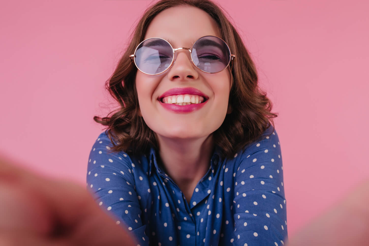 Mulher sorridente de óculos escuros exibe dentes brancos alinhados com lentes de contato dental na Smile Center na ZL de São Paulo.