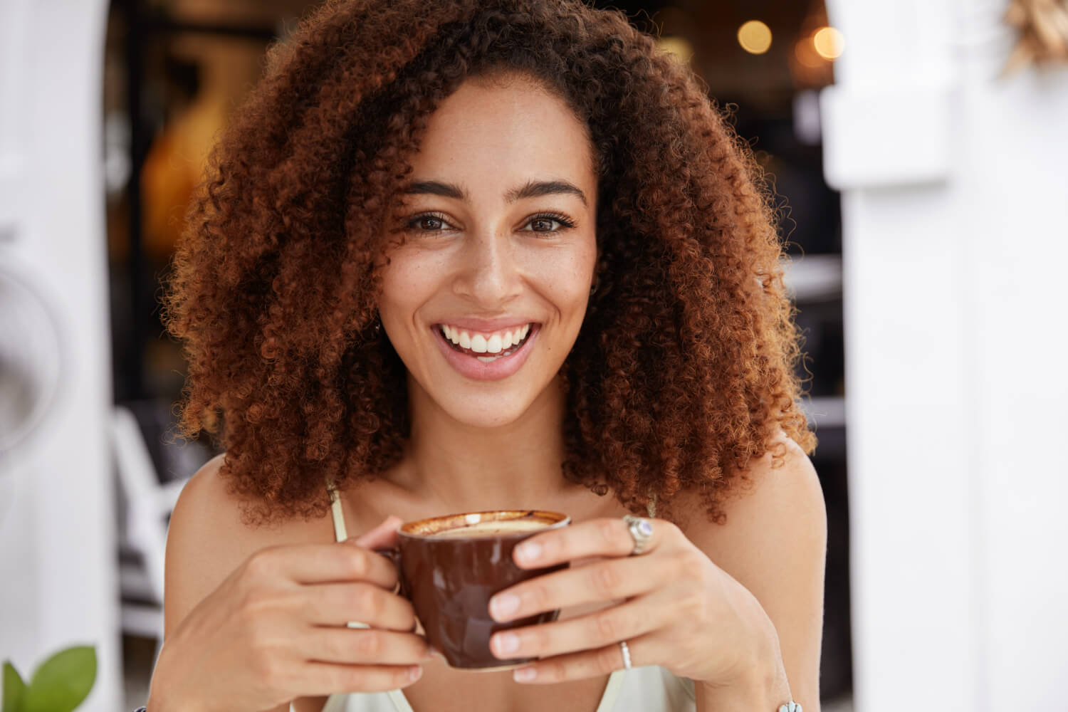 Mulher sorrindo segurando xícara de café para exemplificar se café mancha lentes de contato dental na Zona Leste de São Paulo.